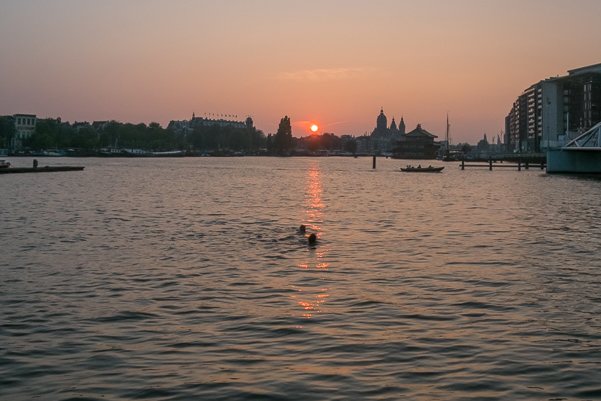 Zwemmen in het Oosterdok bij zonsondergang